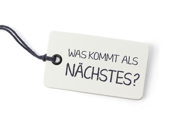 Das Bild zeigt einen kleinen Anh&auml;nger mit dem Schriftzug "Was kommt als N&auml;chstes?"