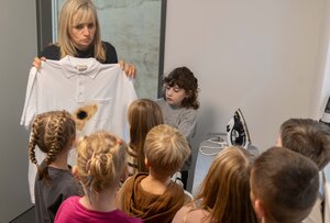 Auf dem Bild sieht man Anja Haymann, die ein verbranntes T-Shirt hochh&auml;lt. ES hat ein Loch von einem B&uuml;geleisen
