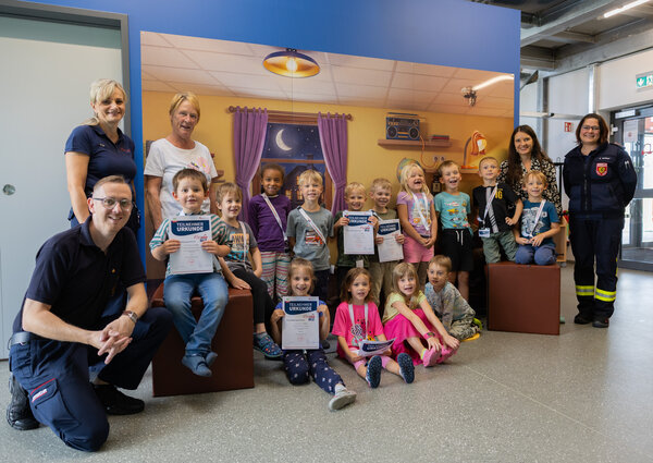 Die Kinder des Kinderland Pausa waren die ersten, die das neue Modul am FloBIZ absolviert haben. Auf dem Bild sitzen sie vor einem Bild eines Kinderzimmers.